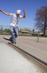 Young man skateboards on a rail