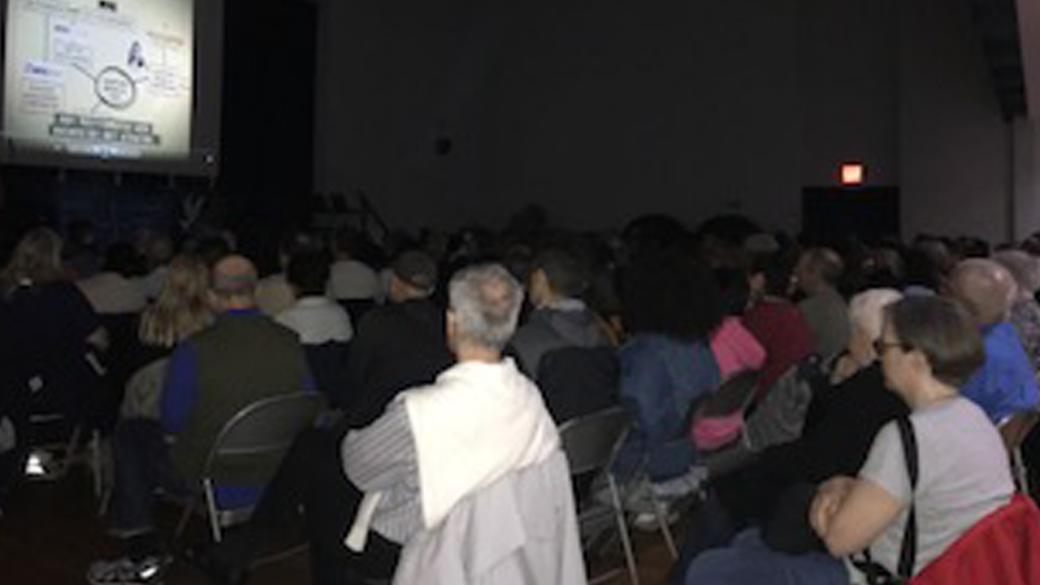 A full audience watches Kelly Anderson's film.