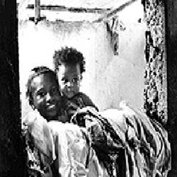 A smiling Afro-Colombian mother holds her toddler child in her arms.