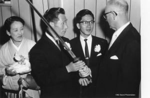 Production still. Nobuo Fujita, accompanied by his wife and son, give samurai sword to Brookings Mayor Fell Campbell. 