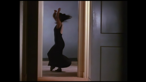 a dancer in a long black dress is seen through a doorway spinning