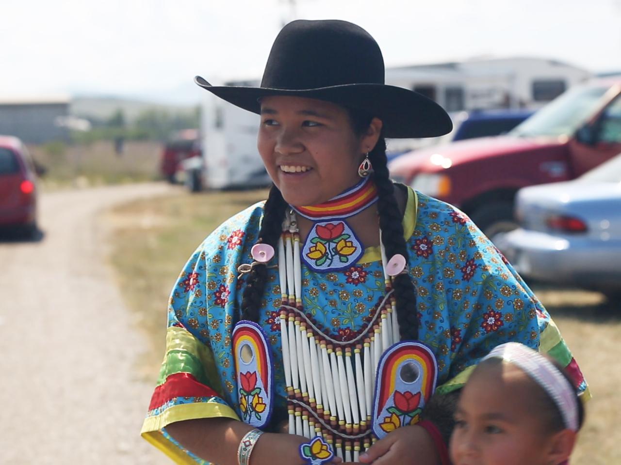 Young Native American Woman in parking lot smiles and looks to the left of the camera lens